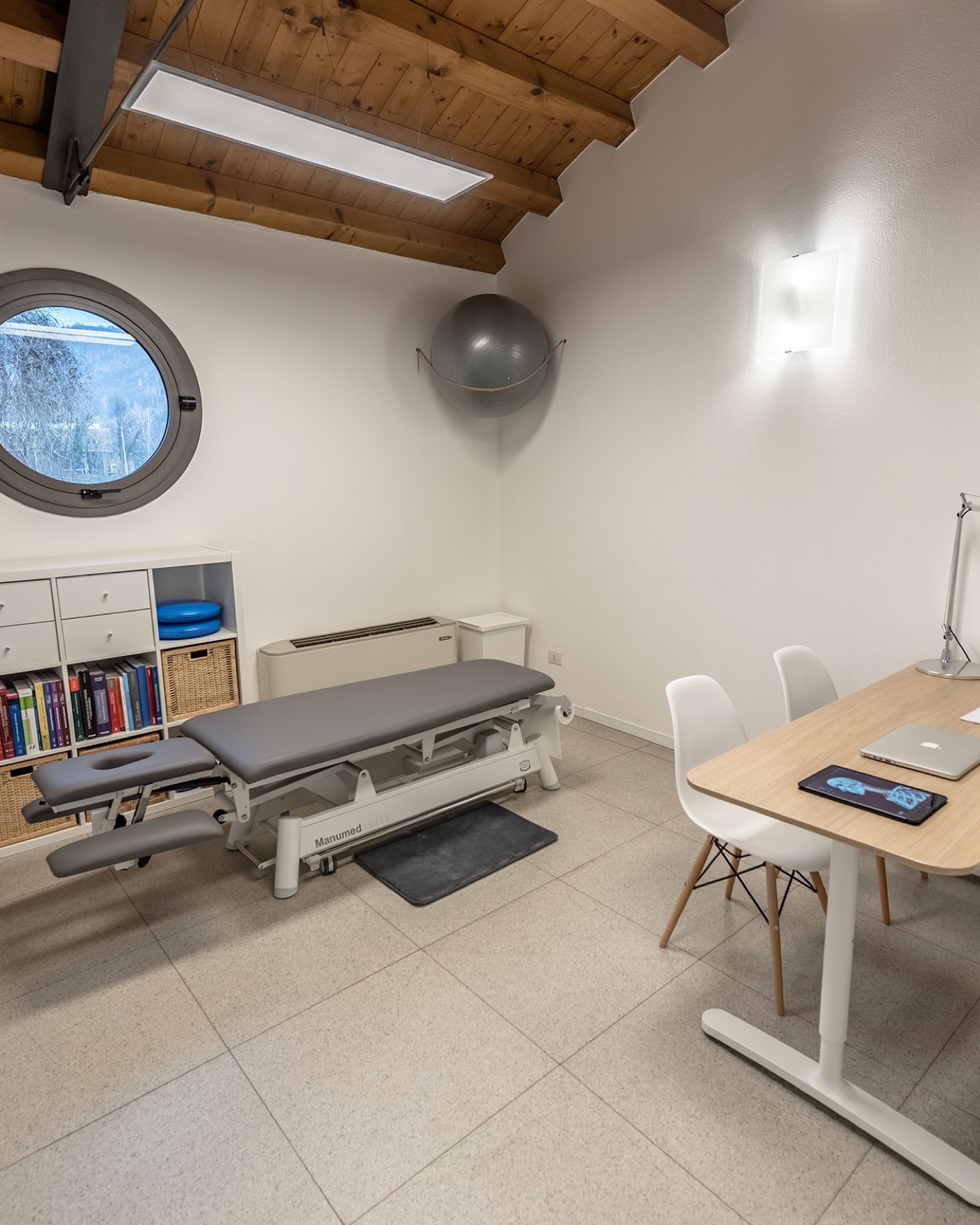 Sala di trattamento fisioterapico con lettino e finestra a oblo